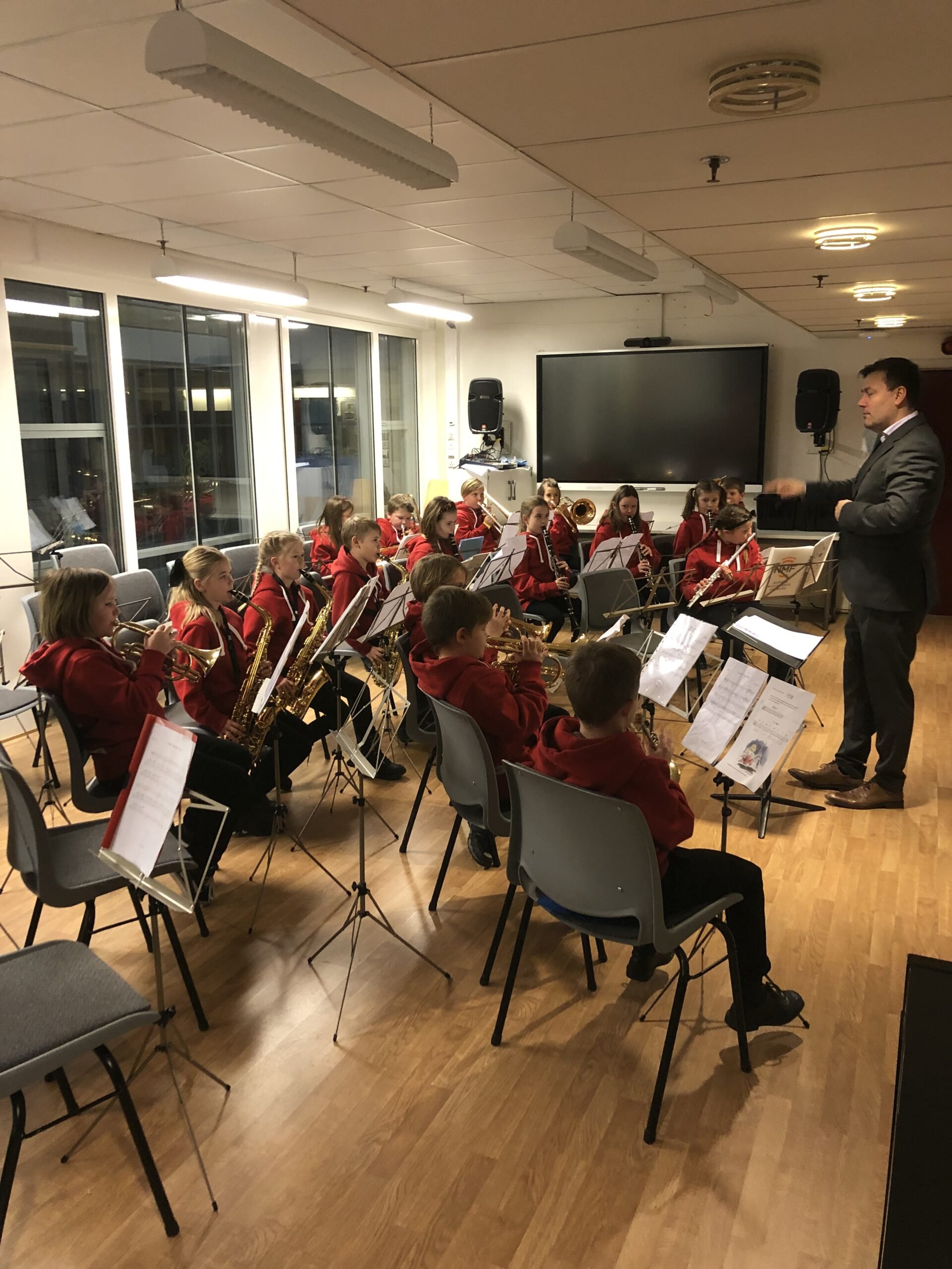 Aspirant- og juniorkorpset spiller konsert innendørs med dirigent