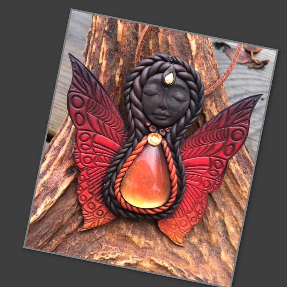 Håndlaget smykke formet som en engel med sommerfuglvinger og rød stein