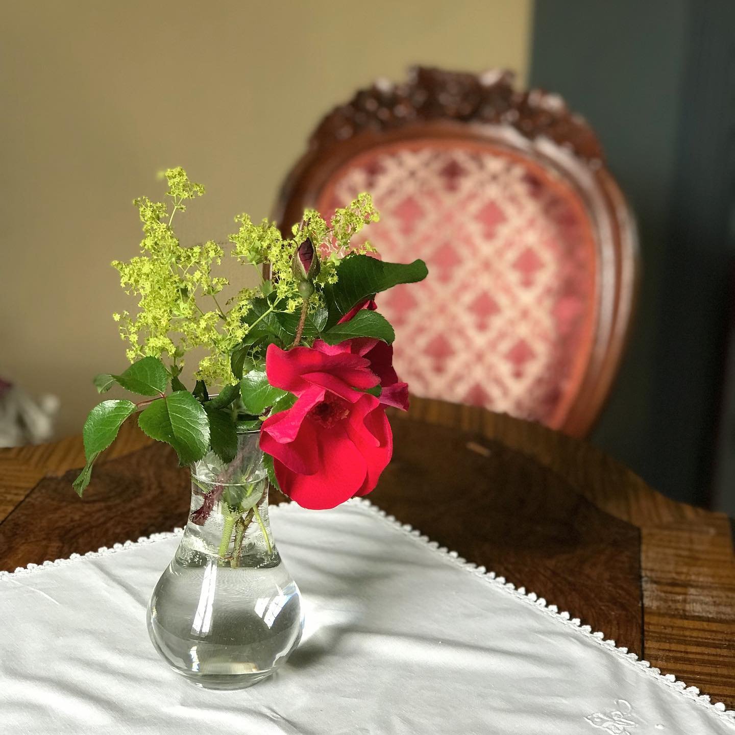 Vase med rød rose og marikåpe på et bord i salongen