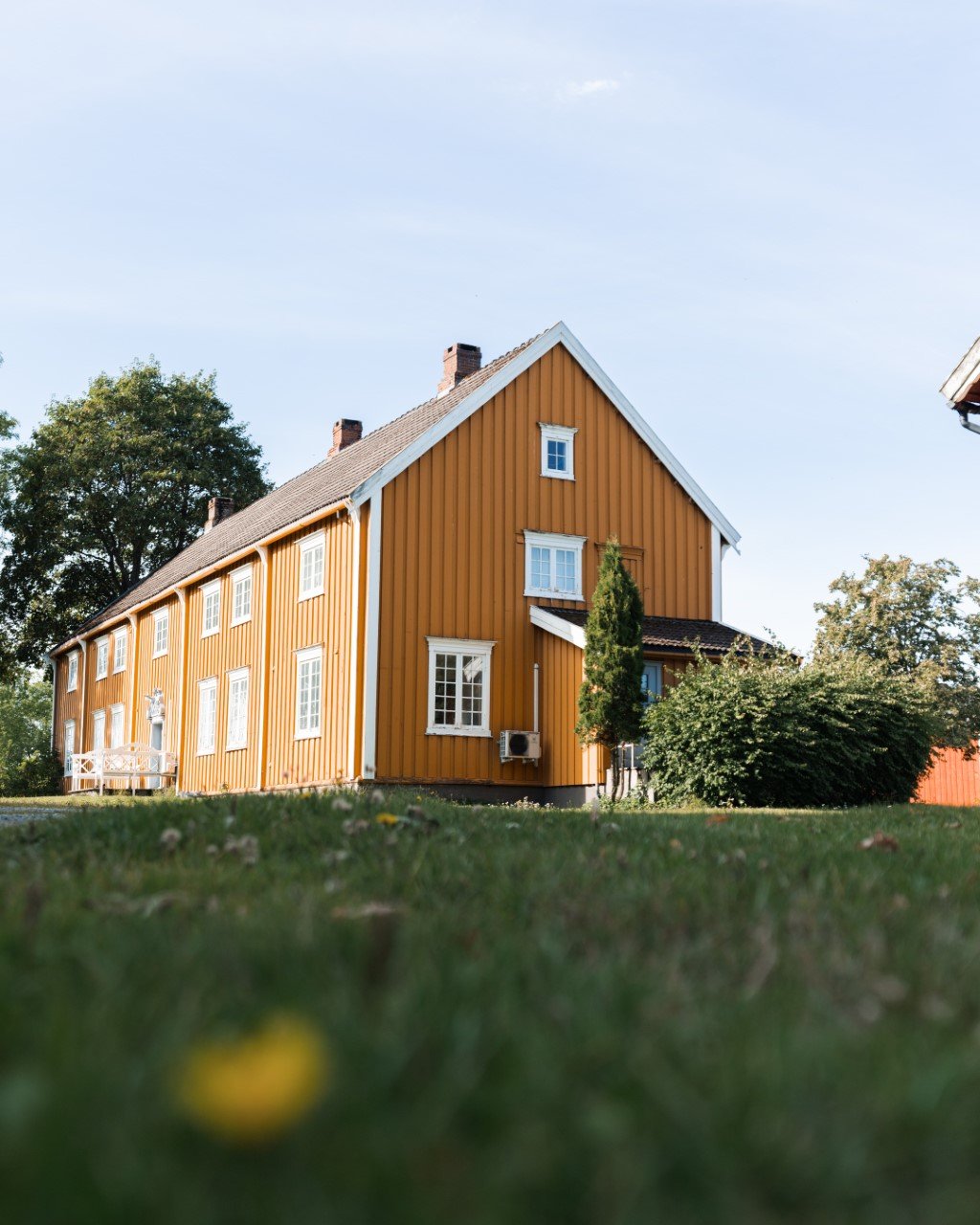 Hovedbygningen på Stadsbygd prestegård, gult trehus i sommersol